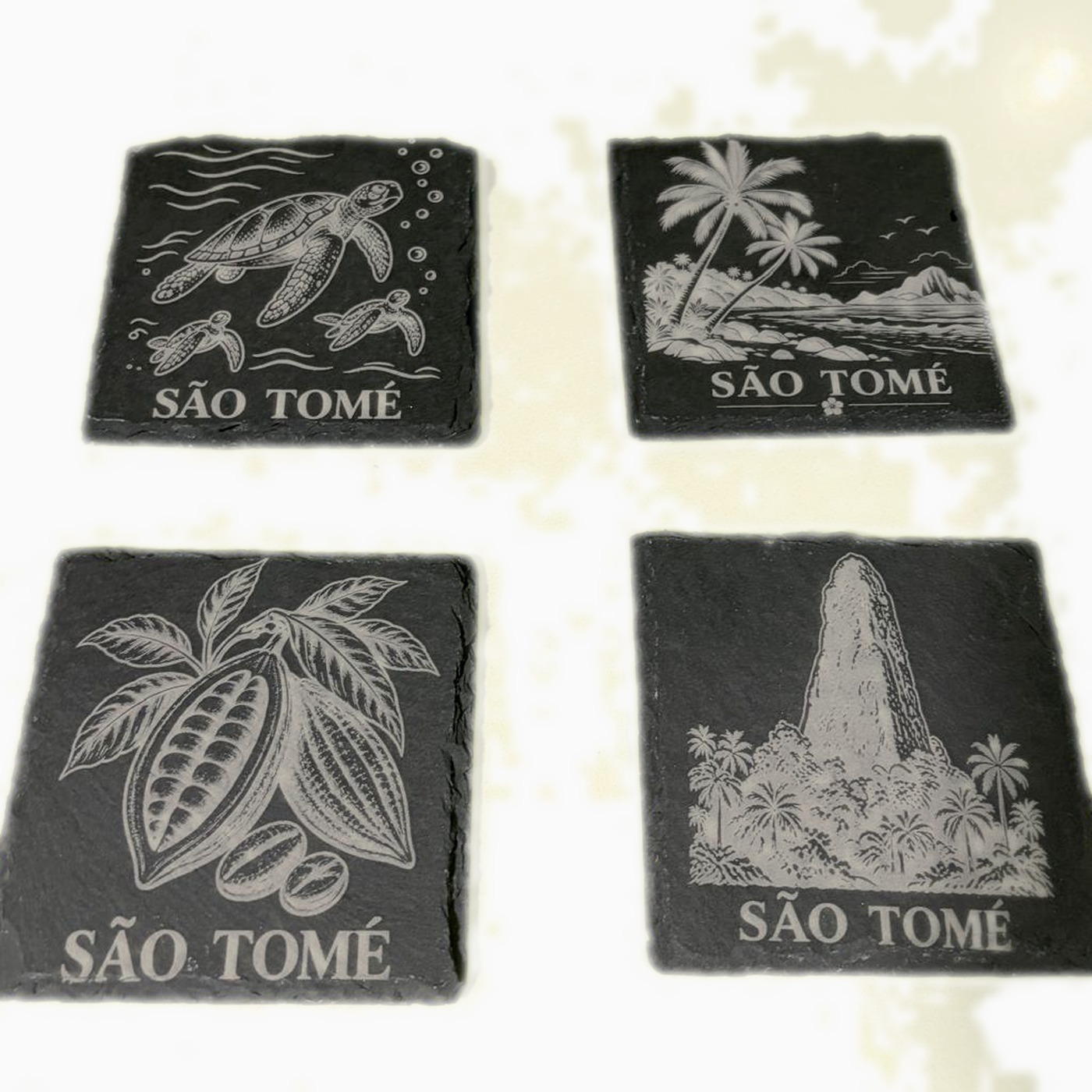 Set de cuatro posavasos de pizarra São Tomé grabados con tortugas, palmeras, cacao y el Pico Cão Grande